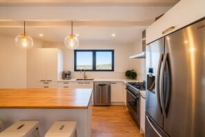 Una cocina moderna con un refrigerador de acero inoxidable, horno empotrado y una cafetera.