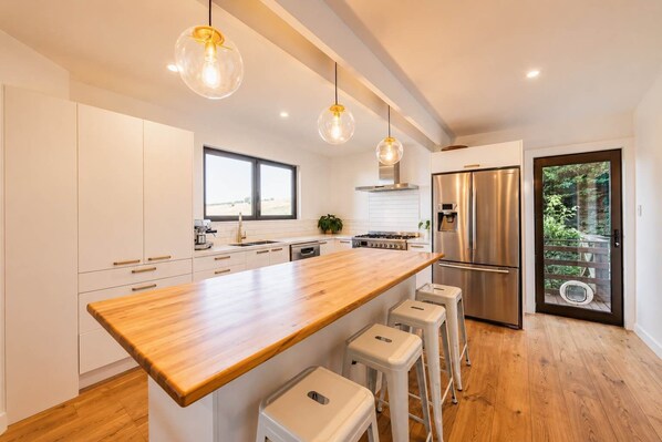 A modern kitchen with a wooden island, stainless steel appliances, and pendant lighting.