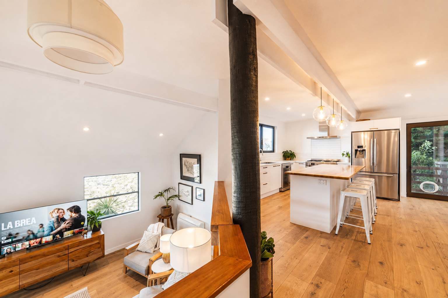 A modern kitchen with a central island, stainless steel appliances, and a large window.