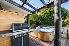 Un patio exterior con una parrilla Rinnai, un jacuzzi y una terraza de madera.