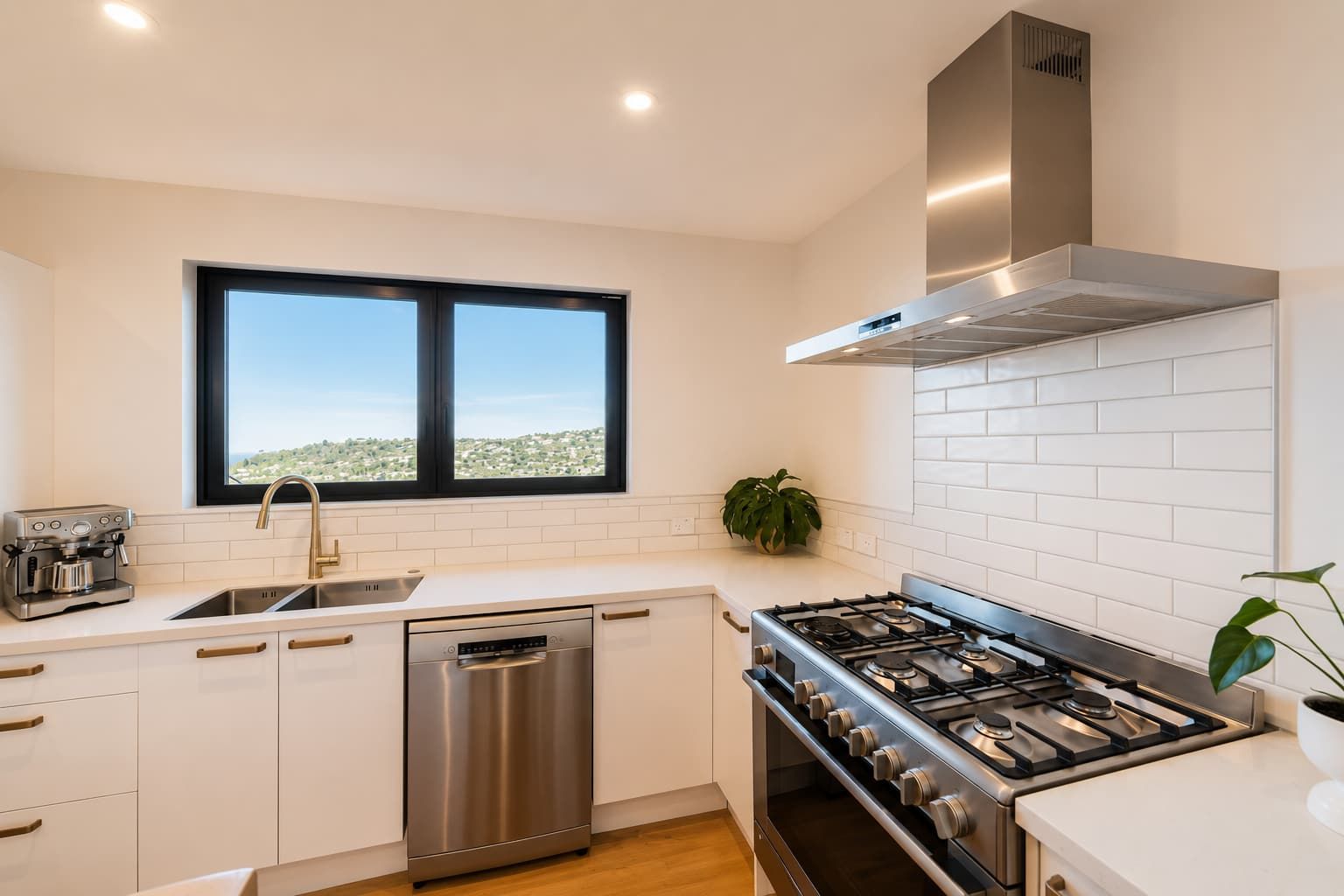 Une cuisine moderne équipée d’un lave-vaisselle, d’une cuisinière et d’une fenêtre donnant sur un paysage urbain.