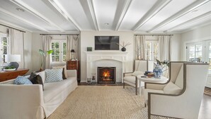 A spacious living room with a fireplace, a sofa, a chair, and a television. - Lakeview Bliss - Beautifully Decorated Home! Close Private Beach! (Harbor Springs)