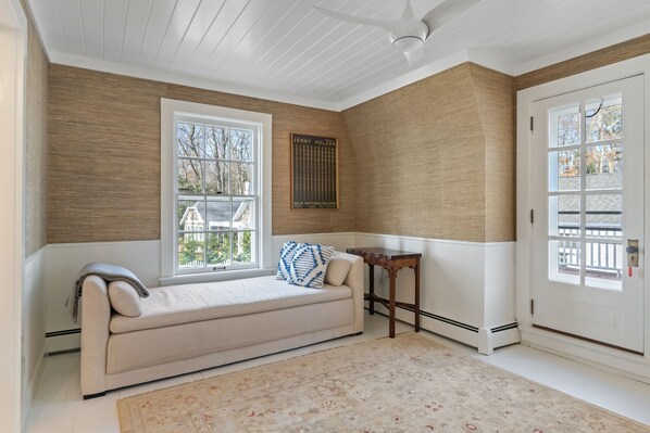 Una habitación acogedora con un sofá color beige, una mesita y una ventana con vistas a árboles.