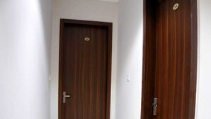 A hallway with two wooden doors, white walls, and a tiled floor. - Hotel Swastik (Amritsar)