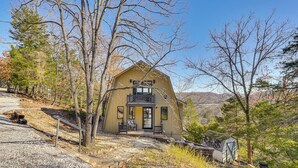 A two-story house with a balcony, surrounded by trees and a gravel driveway. - Fish, Swim & Kayak: Spacious Beaver Lake Home! (Garfield)