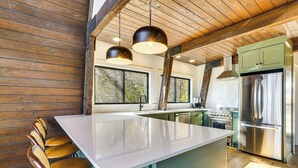 A kitchen with a large island, wooden chairs, and a stainless steel refrigerator. - Fish, Swim & Kayak: Spacious Beaver Lake Home! (Garfield)