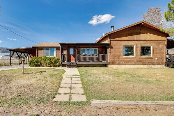 A wooden cabin with a porch, a stone pathway, and a view of the mountains.