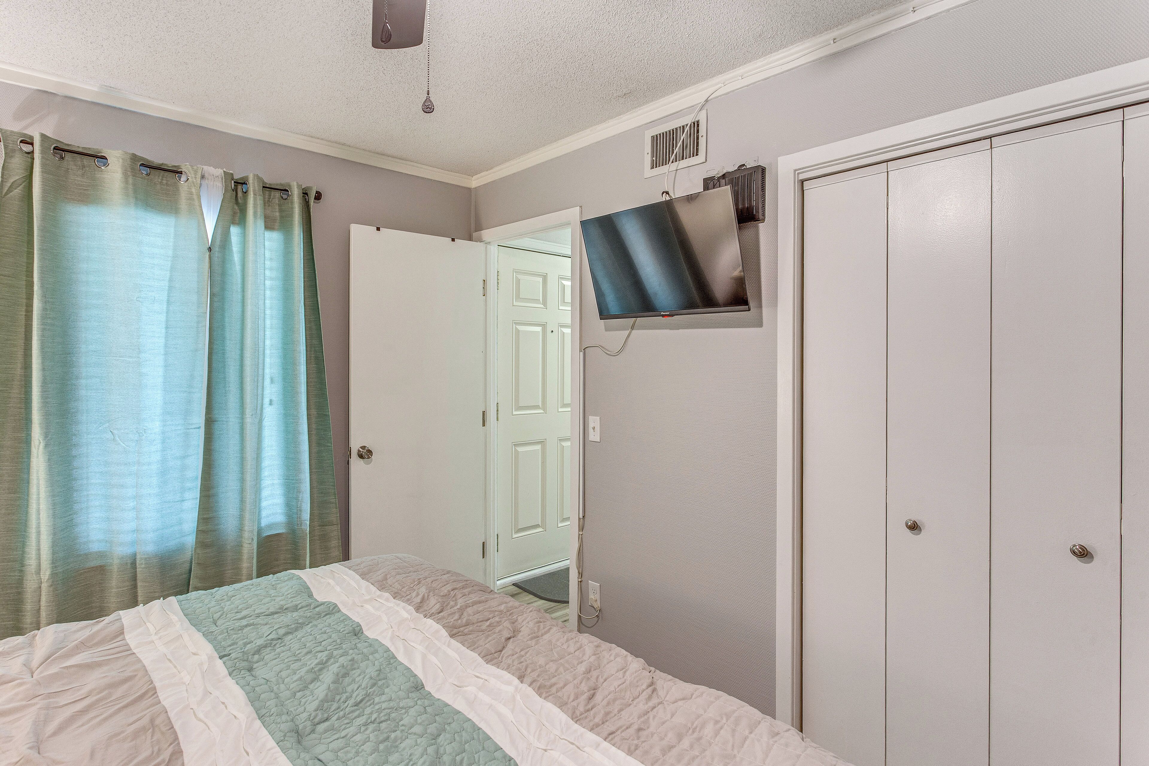 A bedroom with a bed, a television mounted on the wall, and a wardrobe.
