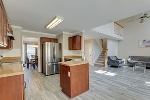 A modern kitchen with a built-in island, stainless steel appliances, and a dining area with a view to the outdoors. - Stone Mountain Vacation Rental With Deck! (Stone Mountain)