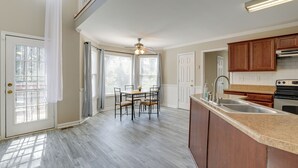 Une cuisine spacieuse dotée d’un grand îlot central, de meubles en bois et d’un coin repas avec une table et des chaises.