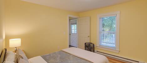 A bedroom with a bed, bedside lamp, and a window with blinds.