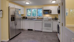 A modern kitchen with white cabinets, stainless steel appliances, and a large window providing natural light. - Walk to Sorrento Town Dock: Pet-friendly Apartment (Sorrento)