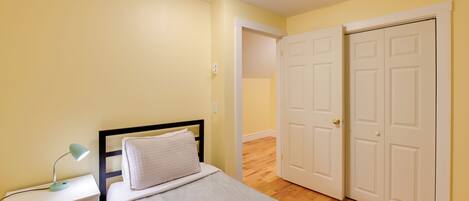A bedroom with a bed, nightstand, lamp, and two doors.
