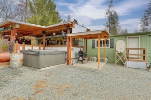 A rustic cabin with a covered patio, a hot tub, and a small outdoor seating area.