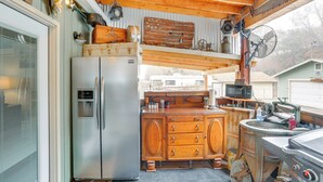 Una cucina compatta con frigorifero, mobili in legno, microonde e una ventola.