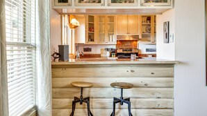 A kitchen with wooden cabinets, a countertop, and two stools. - Spacious Cabin w/ Views, Near Lake Lawtonka! (Medicine Park)