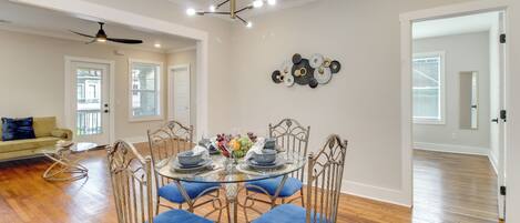 A dining area with a round glass table, blue cushioned chairs, and a chandelier.