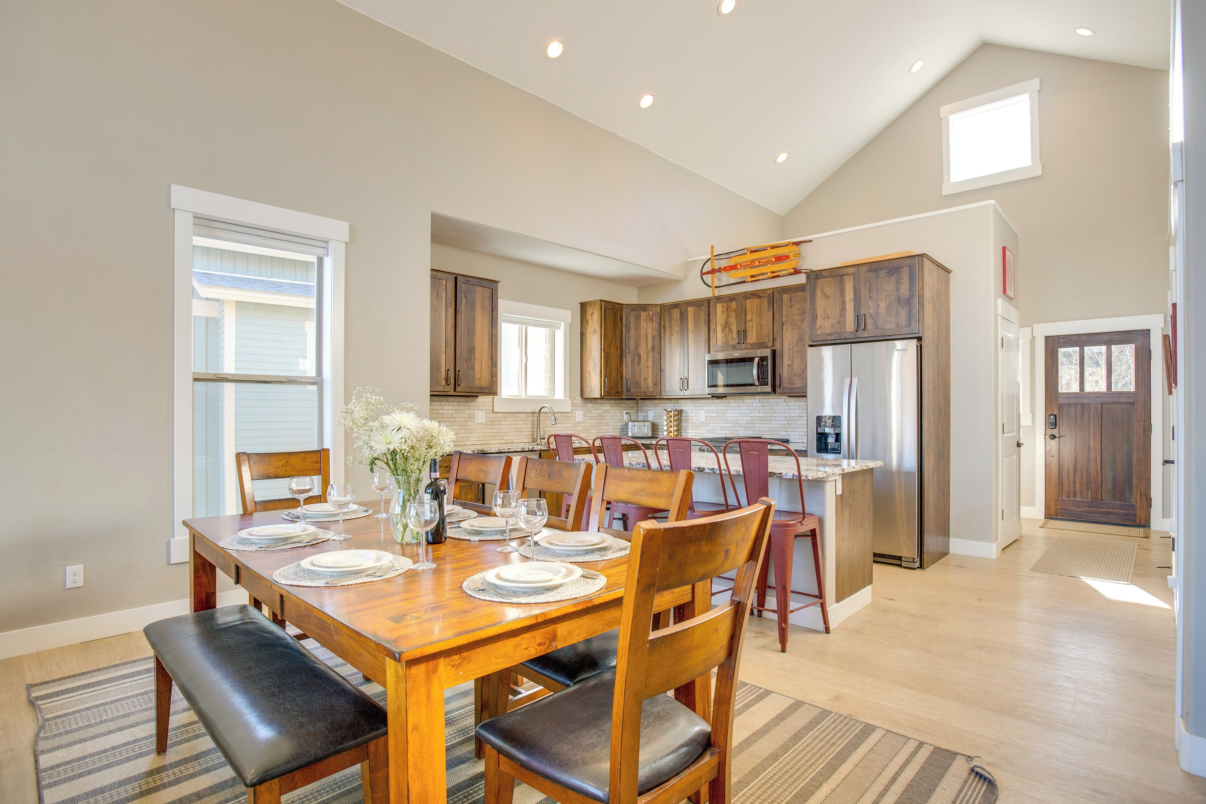 A modern kitchen with wooden cabinets, a stainless steel refrigerator, and a dining area with a wooden table set for four.