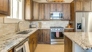 Una cucina con mobili in legno, un frigorifero in acciaio inossidabile, un forno a microonde e un fornello.