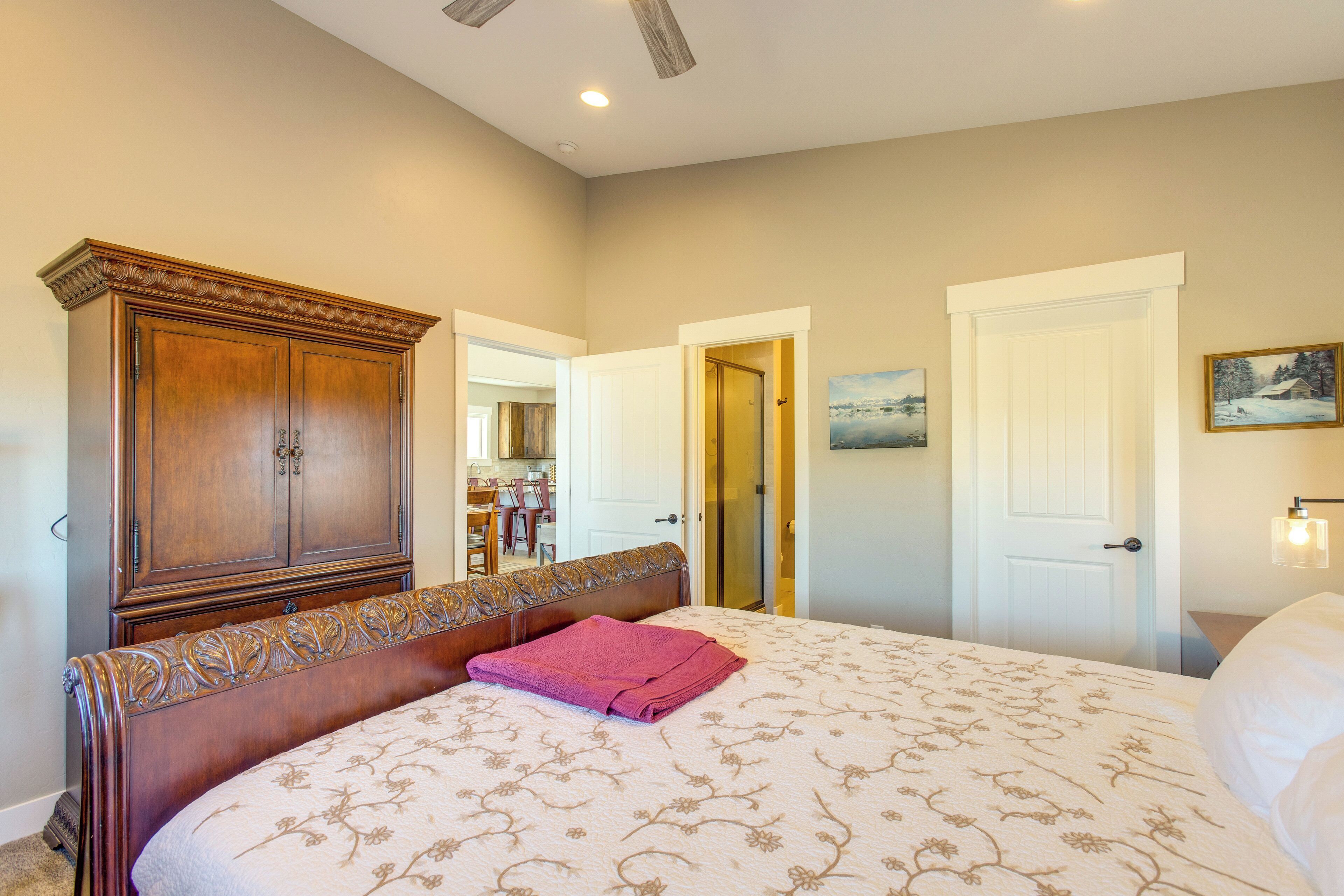 A bedroom with a large bed, a wooden wardrobe, and a door leading to another room.