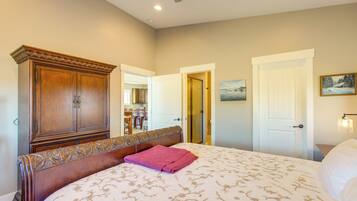 A bedroom with a large bed, a wooden wardrobe, and a door leading to another room.