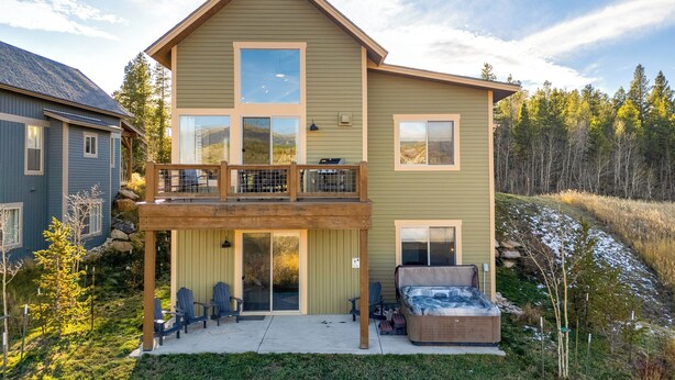 Una casa a due piani con un balcone, una vasca idromassaggio e un patio coperto.
