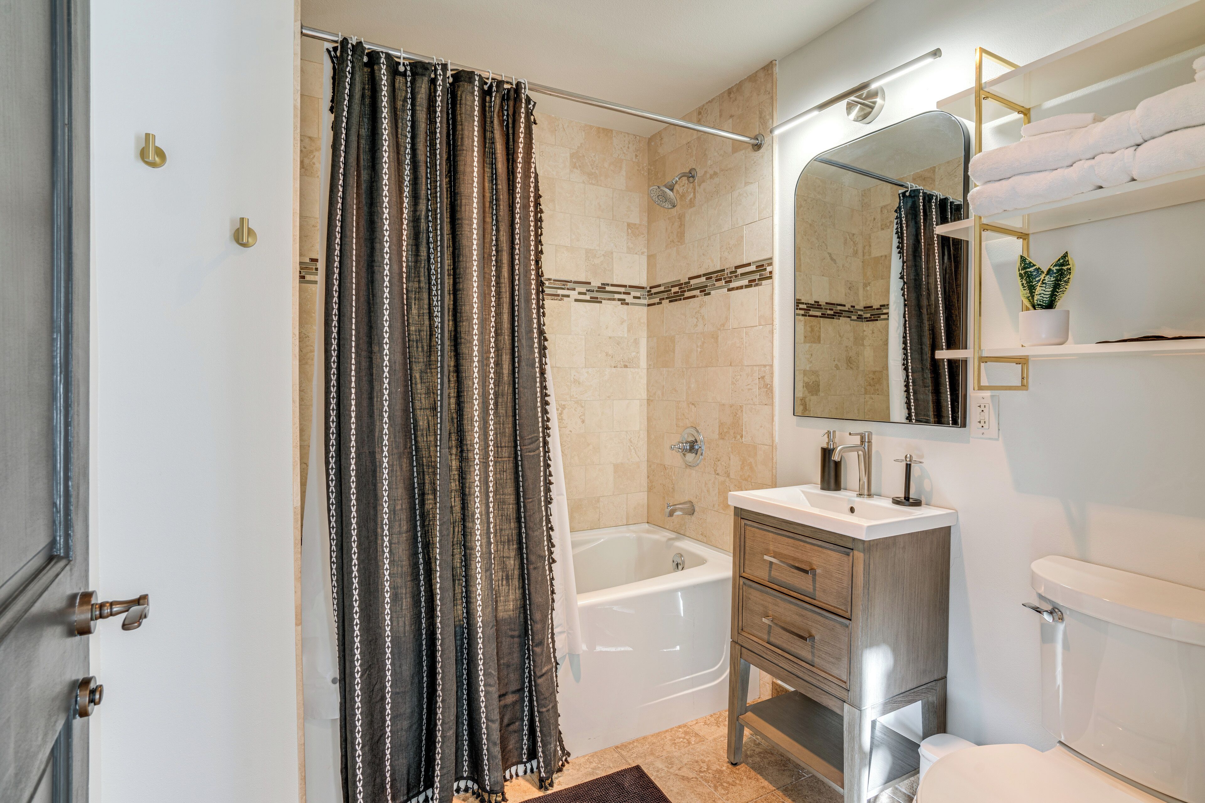 A modern bathroom with a bathtub, a shower, a vanity with a mirror, and a toilet.