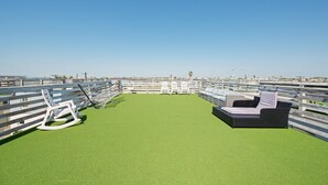 A rooftop terrace with artificial grass, white lounge chairs, and a hammock. - Rooftop Terrace, Panoramic Deck, Pool & Near Beach (Port Aransas)