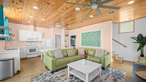 A modern kitchen with white appliances, a green sofa, and a ceiling fan. - Rooftop Terrace, Panoramic Deck, Pool & Near Beach (Port Aransas)