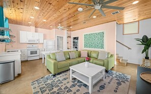 A modern kitchen with white appliances, a green sofa, and a ceiling fan. - Rooftop Terrace, Panoramic Deck, Pool & Near Beach (Port Aransas)