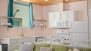 A compact kitchenette with white cabinets, a microwave, a stove, and a refrigerator. - Rooftop Terrace, Panoramic Deck, Pool & Near Beach (Port Aransas)
