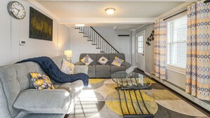 A living room with a sofa, coffee table, and a staircase leading to another level. - Home Near Skiing & Downtown Worcester (Worcester)