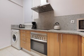 A compact kitchen with a washing machine, oven, microwave, kettle, and coffee maker. - Great Acomodis Apartment In the heart of the Gothic Quarter-Live Barcelona! (Barcelona)
