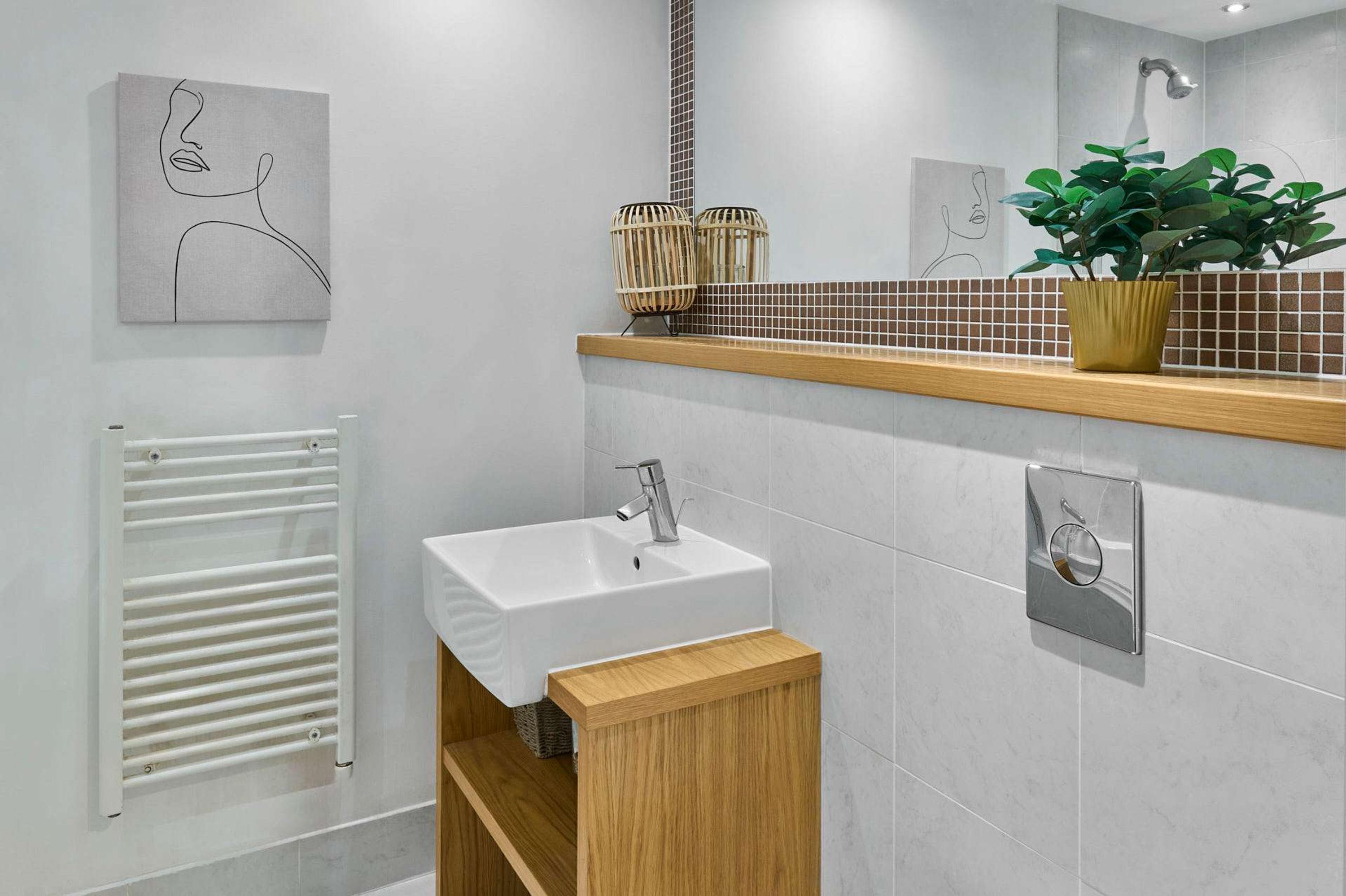 Ein modernes Badezimmer mit Waschbecken, Spiegel, Handtuchhalter und einer Topfpflanze.