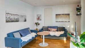 A modern living room with a blue sofa, a round coffee table, and a white fireplace.