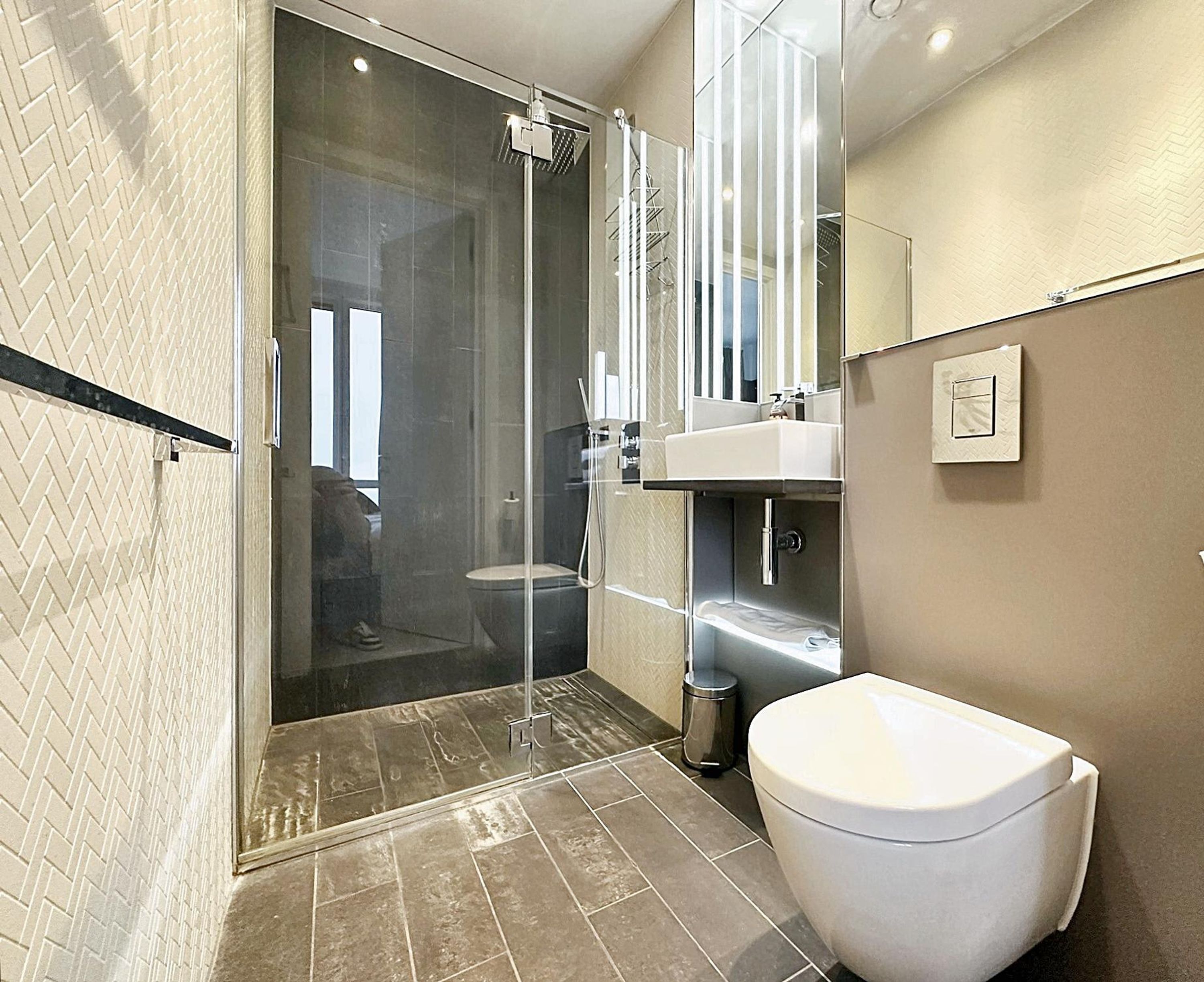 Een moderne badkamer met een douchecabine van glas, een wit toilet en een wastafel met een spiegel erboven.