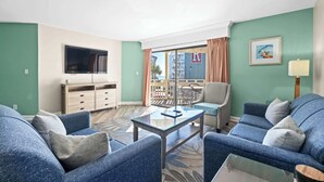 A living room with two sofas, a coffee table, a TV, and a balcony with a view. - Coastal Vista, Steps to Beach/Pool (By Beach Star) (Myrtle Beach)