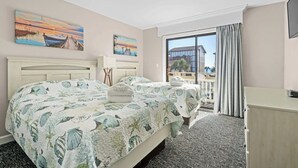 A hotel room with a bed, a desk, and a view of the outside. - Coastal Vista, Steps to Beach/Pool (By Beach Star) (Myrtle Beach)