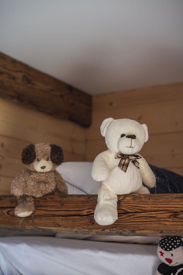 A wooden bunk bed with two stuffed animals on it.