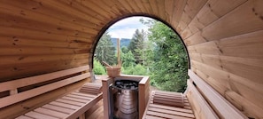 A sauna with wooden benches and a view of a forest through a circular opening.