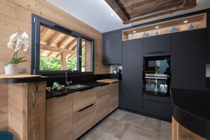 A modern kitchen with wooden cabinetry, a black countertop, and a built-in oven.