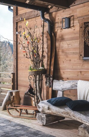 A rustic wooden cabin with a bench, a decorative tree branch, and a metal pipe.