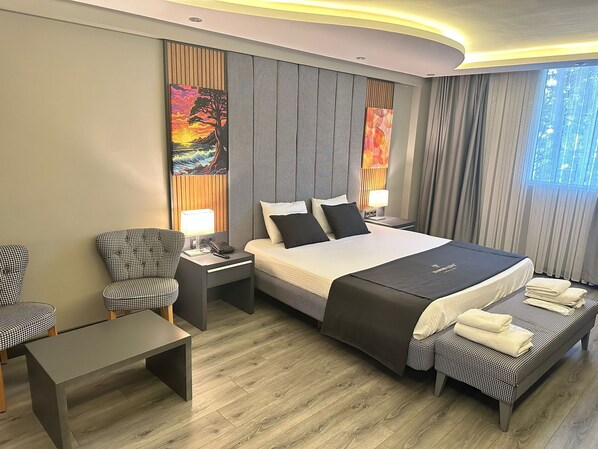 Une chambre d’hôtel moderne avec un grand lit, deux tables de chevet, un bureau et deux chaises.