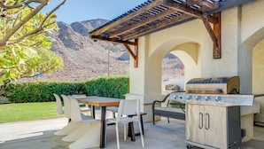 Eine Außenpatio mit Grill, Sitzgelegenheiten und Blick auf Berge.