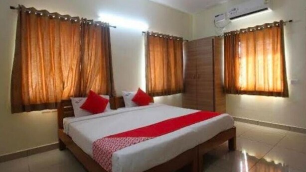 A bedroom with a bed, curtains, and a wardrobe. - Sethu Residency (Thindukkal)