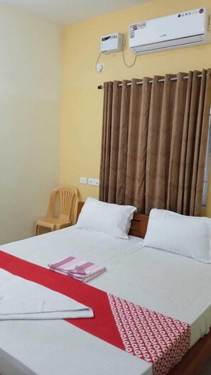 A hotel room with a bed, a chair, and an air conditioning unit. - Sethu Residency (Thindukkal)
