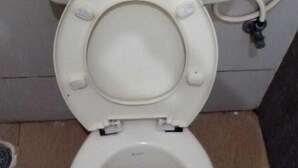 A toilet with a closed lid, a visible flush handle, and a visible flush button. - Sethu Residency (Thindukkal)
