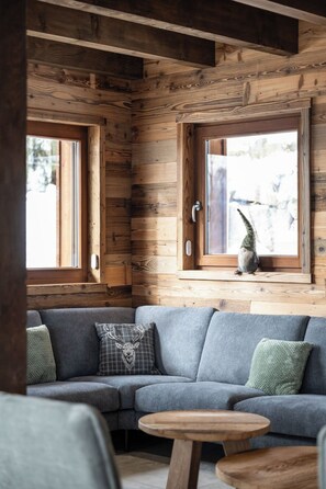 A cozy room with a wooden interior, a gray sectional sofa, and a round wooden table.