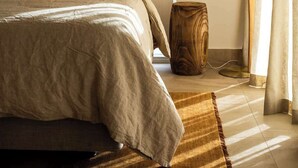 A modern bedroom with a bed, a wooden side table, a floor lamp, and a view of the outdoors through curtains. - Hygge House - 300m to the beach (Aldinga Beach)
