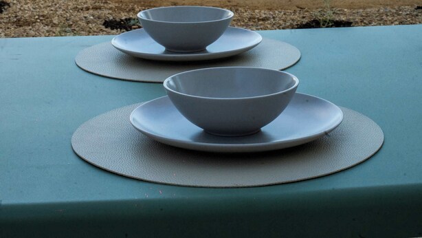 A table set with bowls and plates in an outdoor area with a view of hills and a white fence. - Hygge House - 300m to the beach (Aldinga Beach)